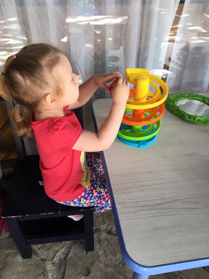 Child playing with a colorful ball run toy on a table