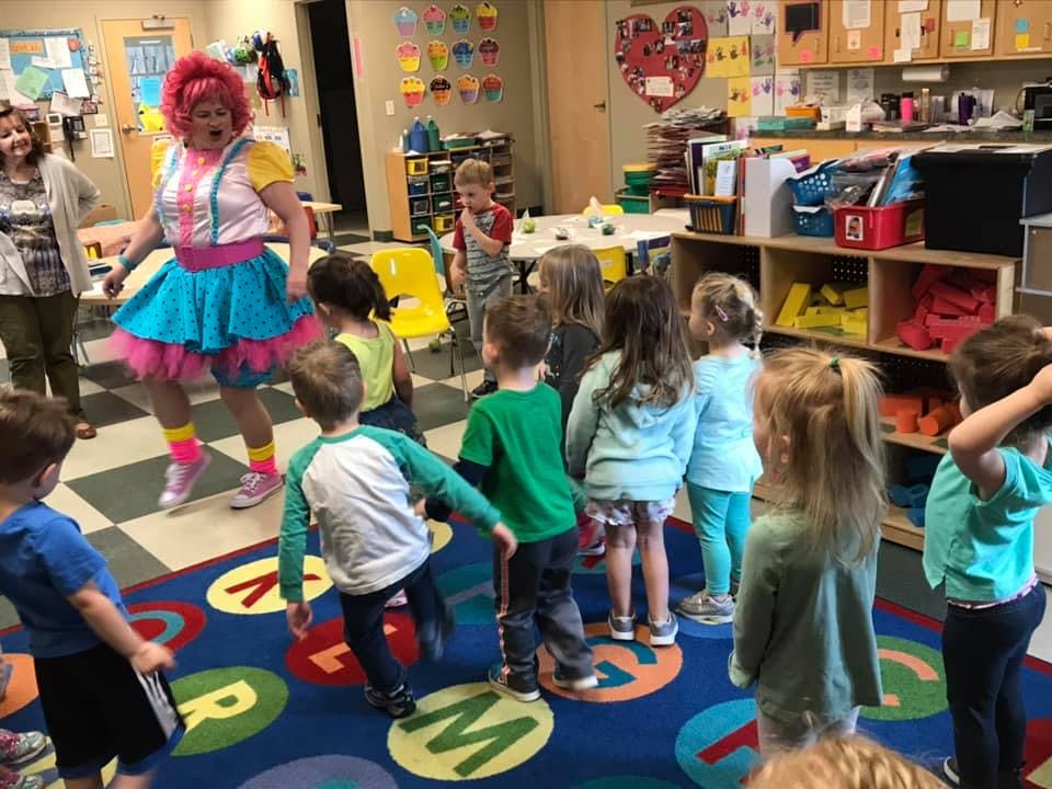 Person in colorful costume dancing with children in a classroom