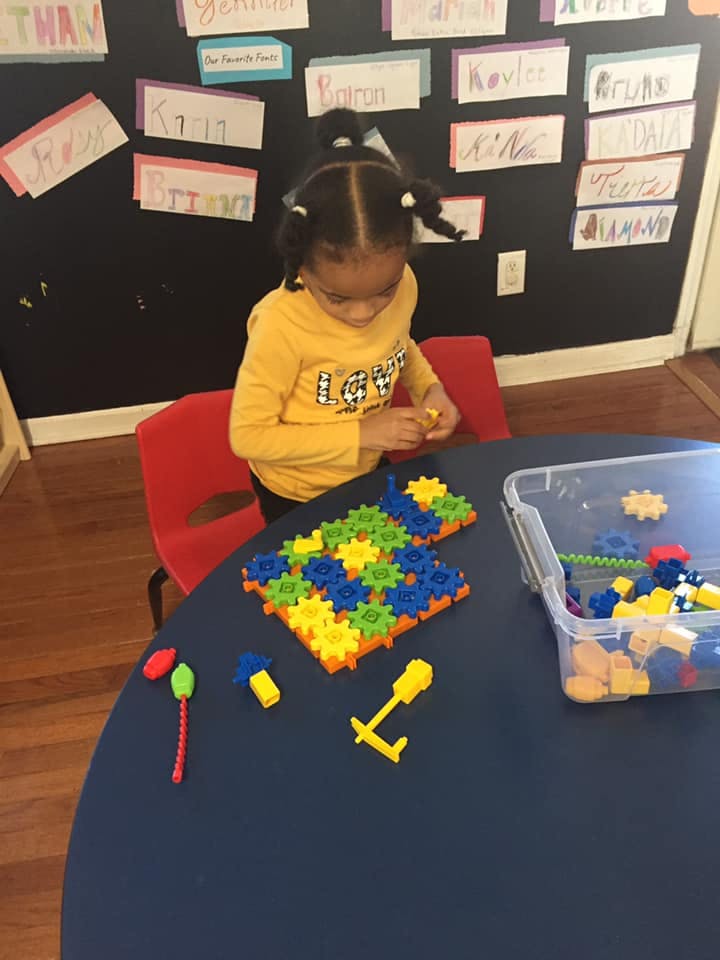 Child playing with colorful interlocking gears at a table