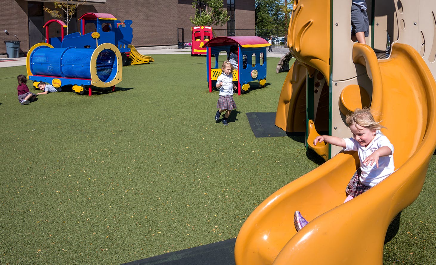 Child sliding down a yellow slide on a playground