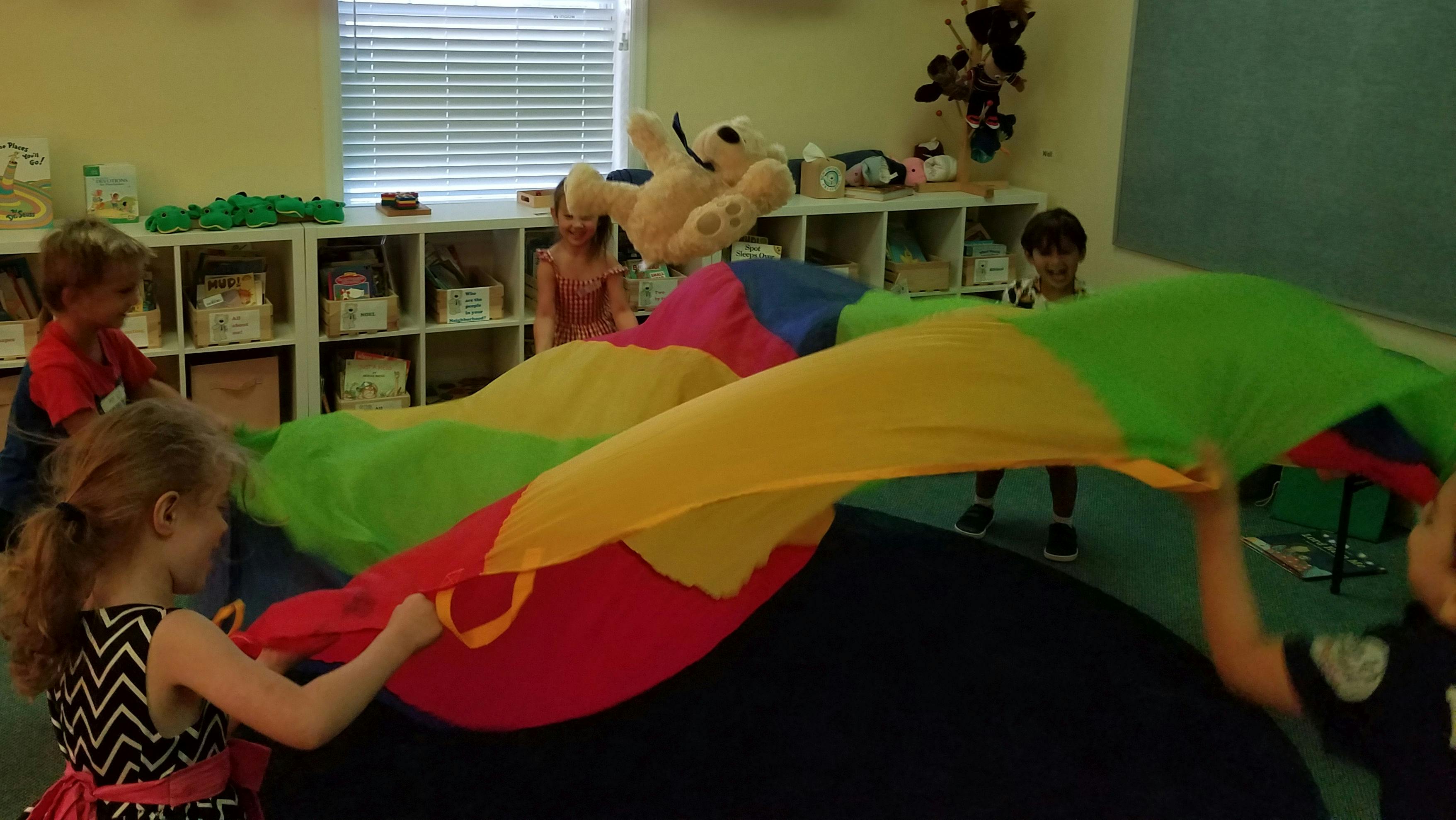 Children playing with a colorful parachute in a classroom