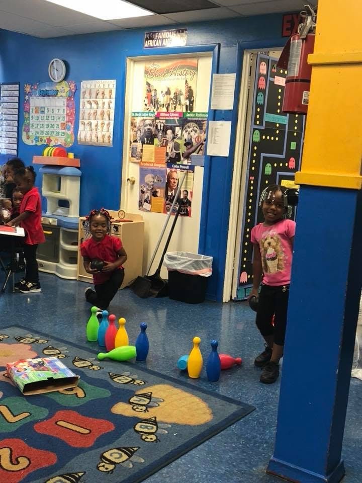 Children playing with bowling pins in a classroom