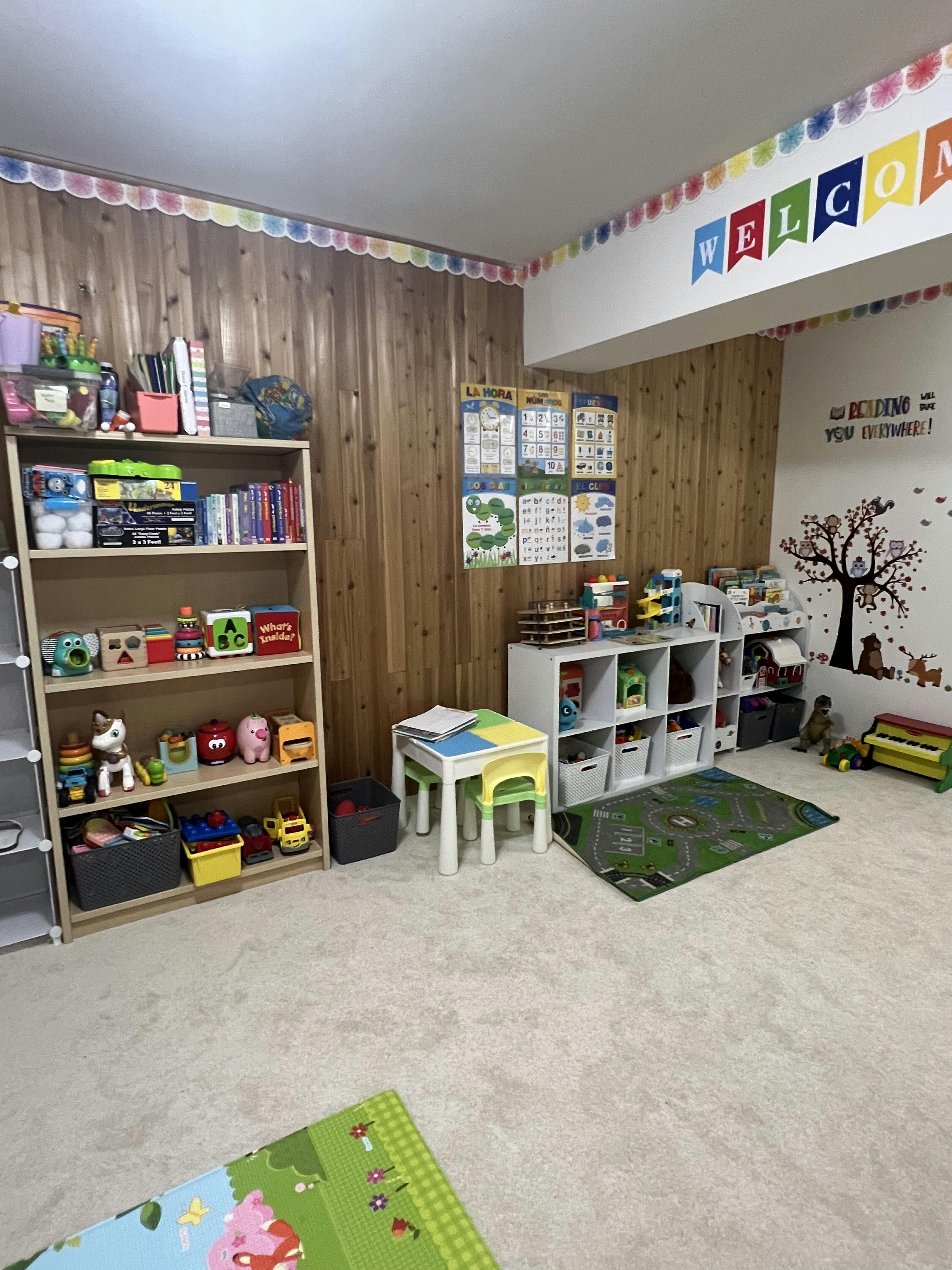 Playroom with shelves of toys, small table and chairs, and welcome banner