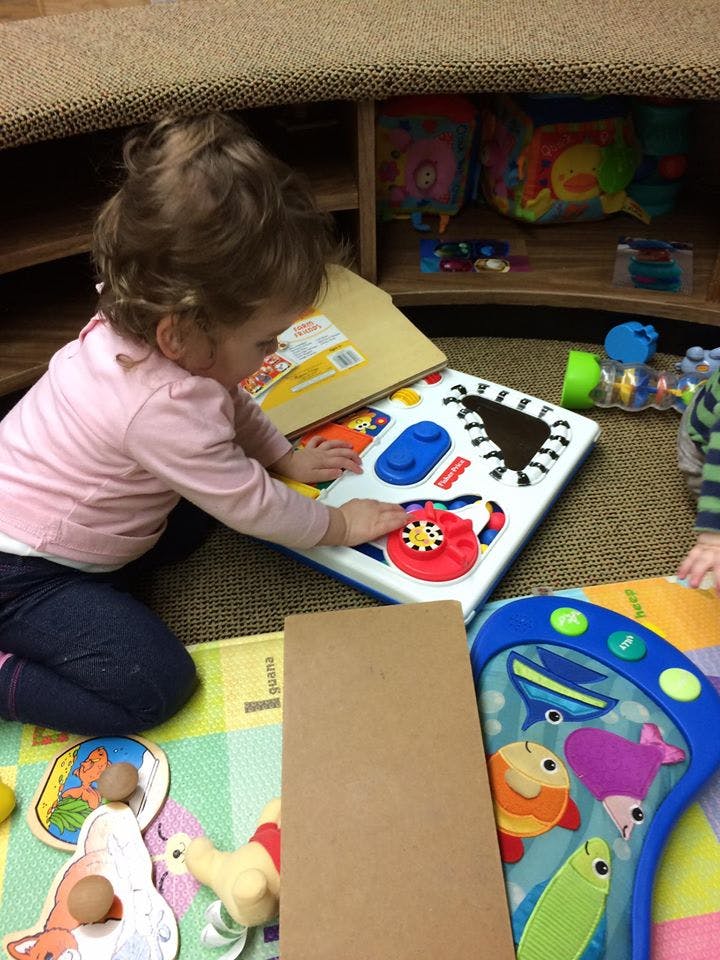 Child playing with an activity board on the floor