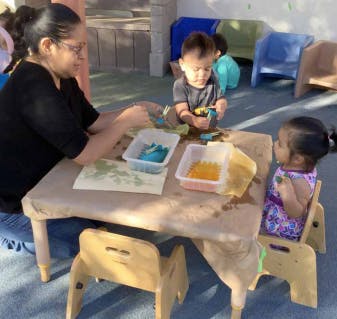 Adult and two children at a table with art supplies