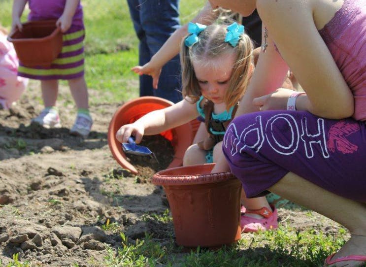 Child playing with dirt and pots outdoors