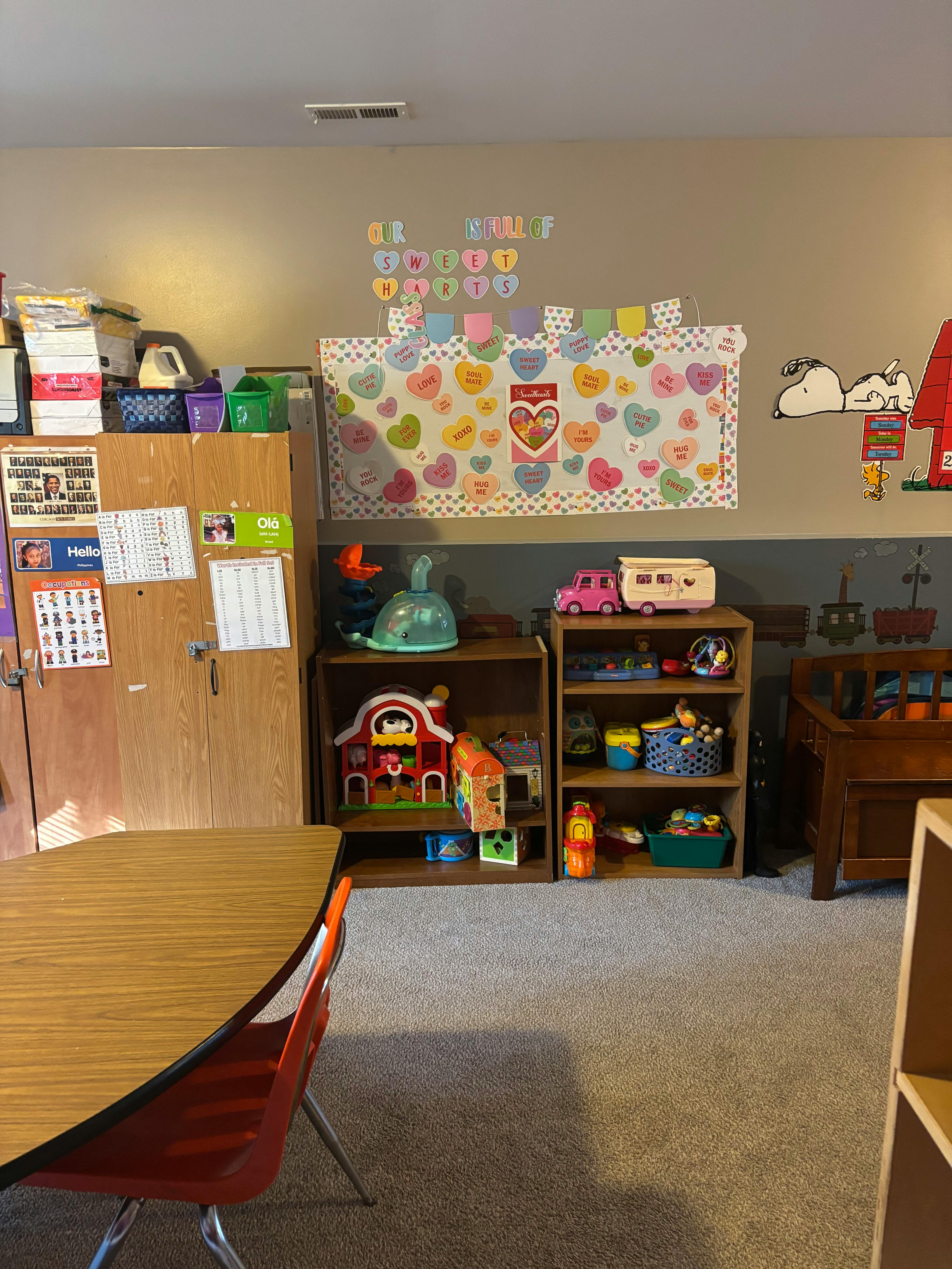 Classroom with heart decorations, wooden cabinets, and toy shelves