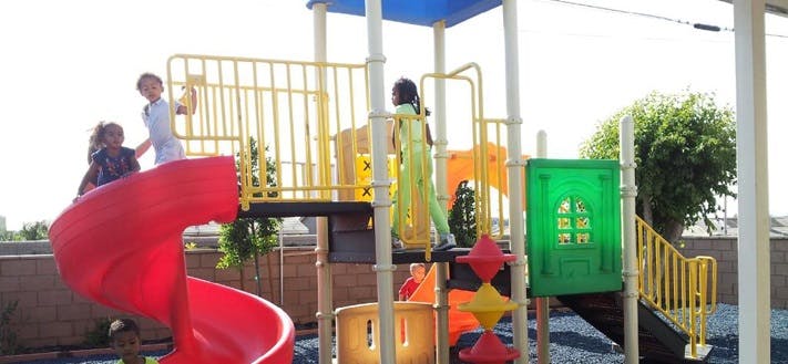Children playing on a playground structure with a red slide