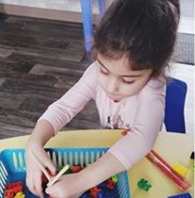 Child playing with building blocks in a blue basket
