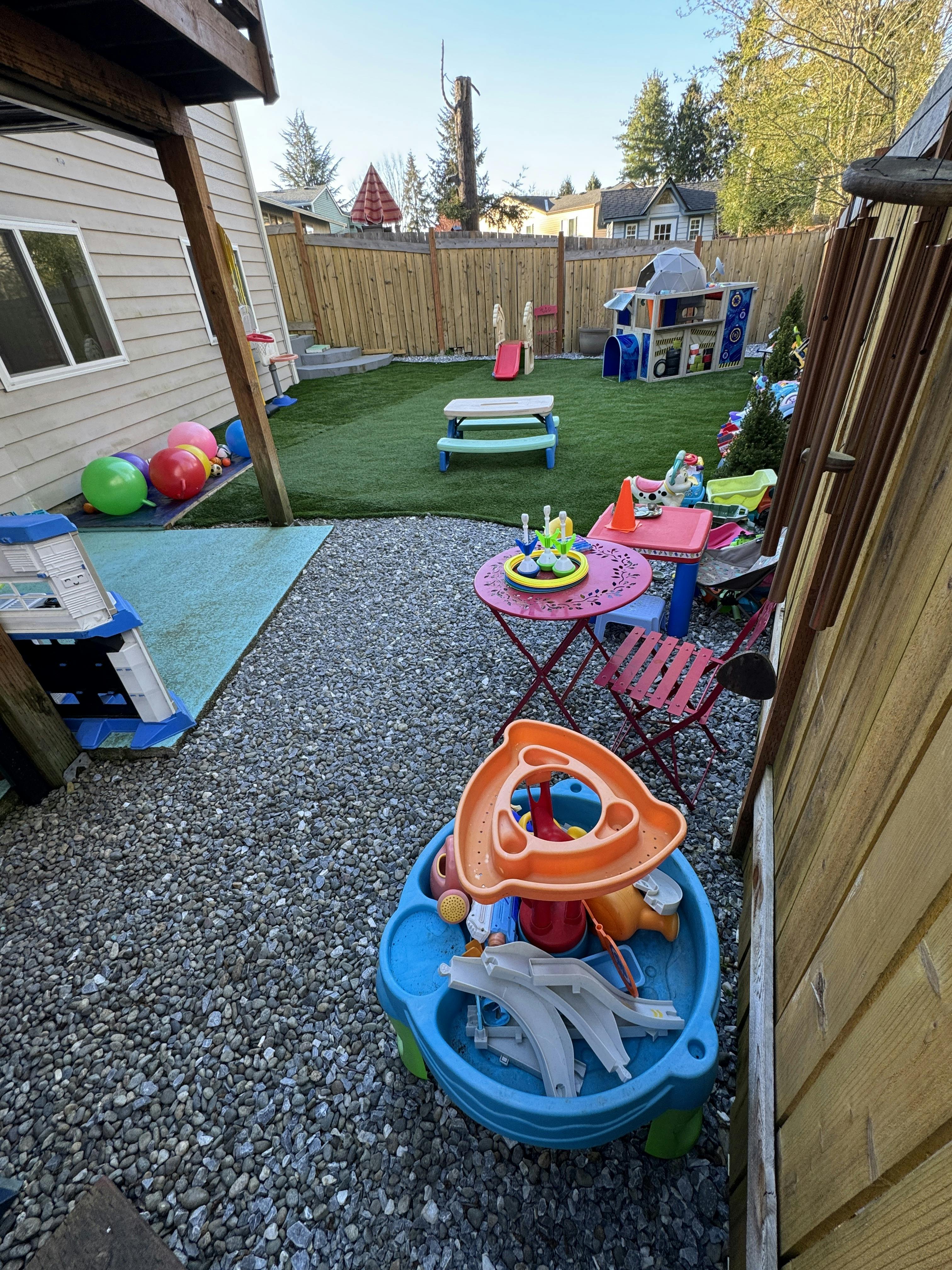 Backyard with artificial turf, children's toys, and gravel areas