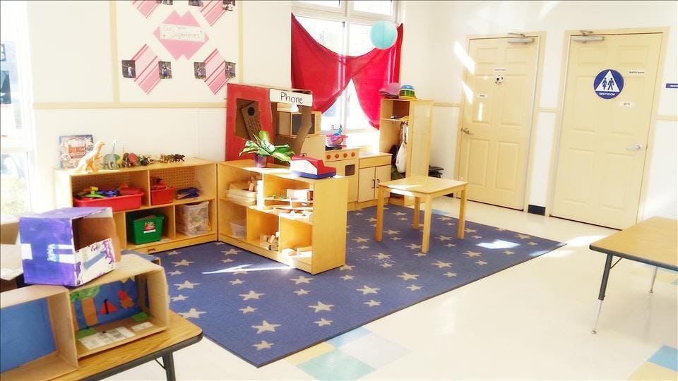 Playroom with star-patterned rug, toy kitchen, shelves, and small tables