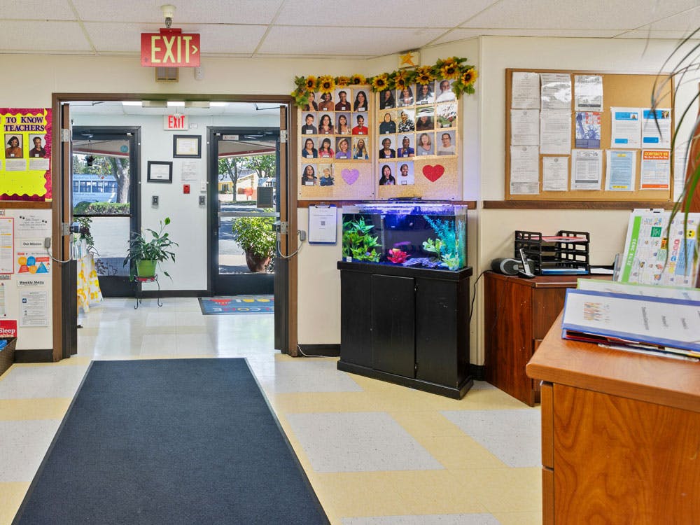 Hallway with an EXIT sign above double doors, a fish tank, and bulletin boards