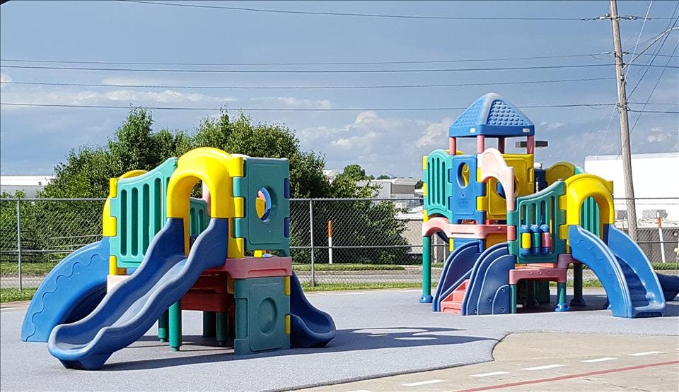 Colorful plastic playground equipment with slides and platforms on a soft ground surface