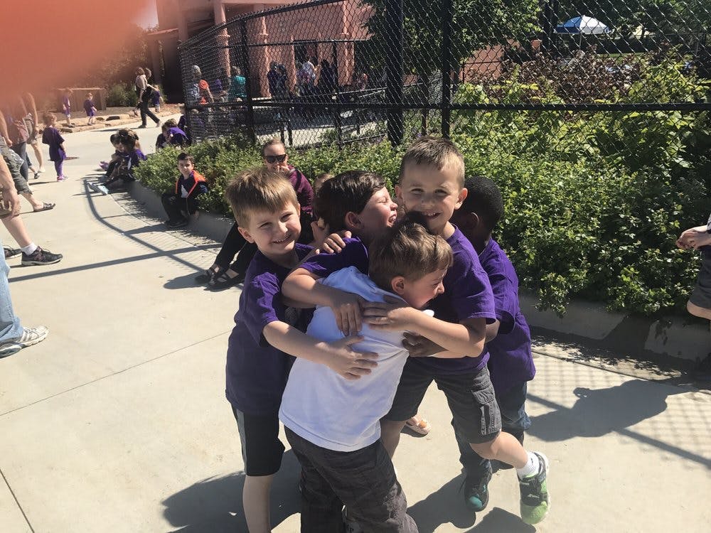 Group of children in purple shirts hugging