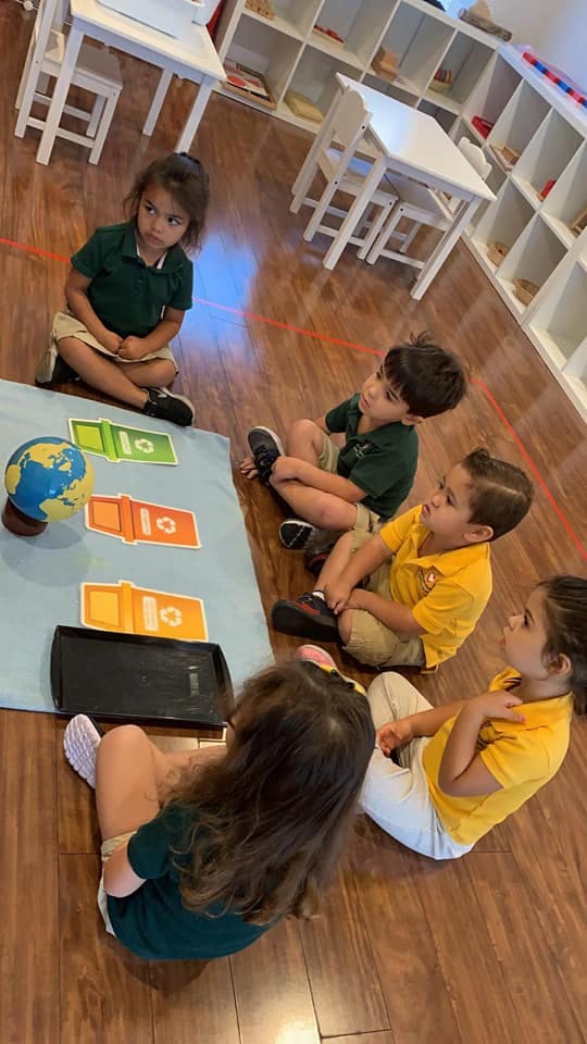 Children sitting on the floor around a globe and cards