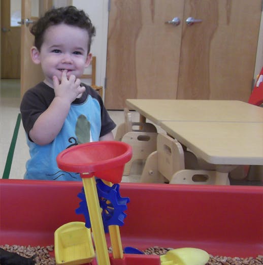 Child with hand to mouth in a classroom