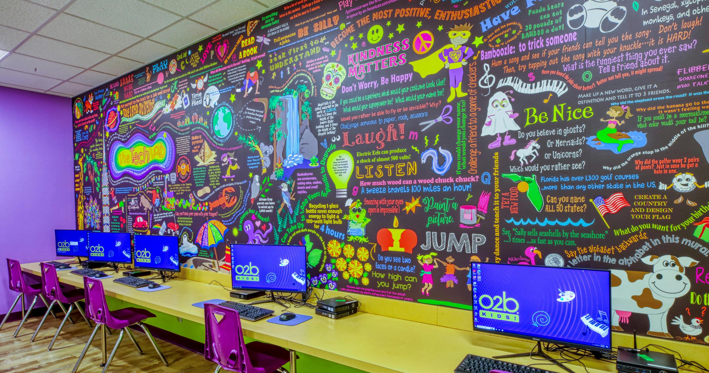A colorful mural with computers lined up against a wall
