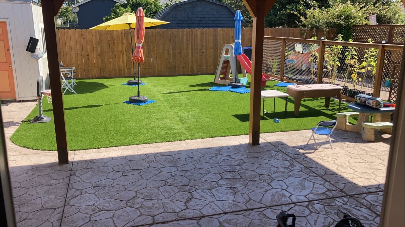 Backyard with artificial turf, patio, and play equipment