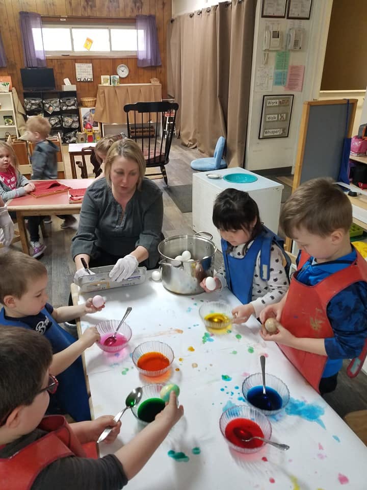 Adult and children dyeing eggs at a table