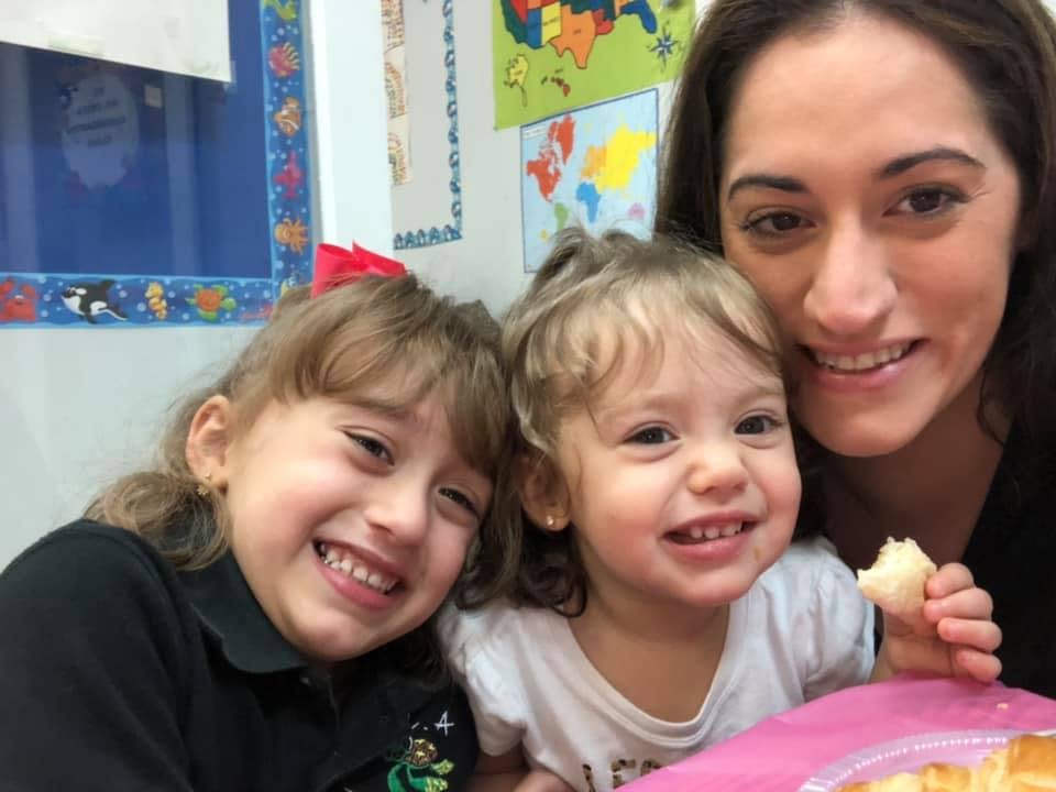 Adult and two children smiling, one child holding food