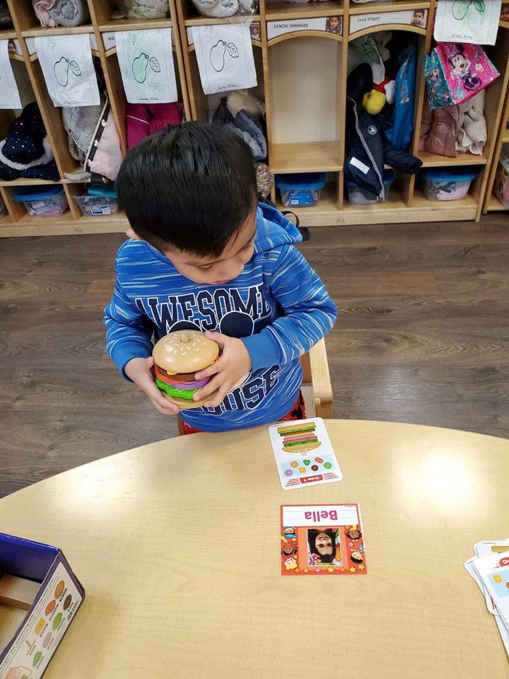 Child holding a toy hamburger at a table
