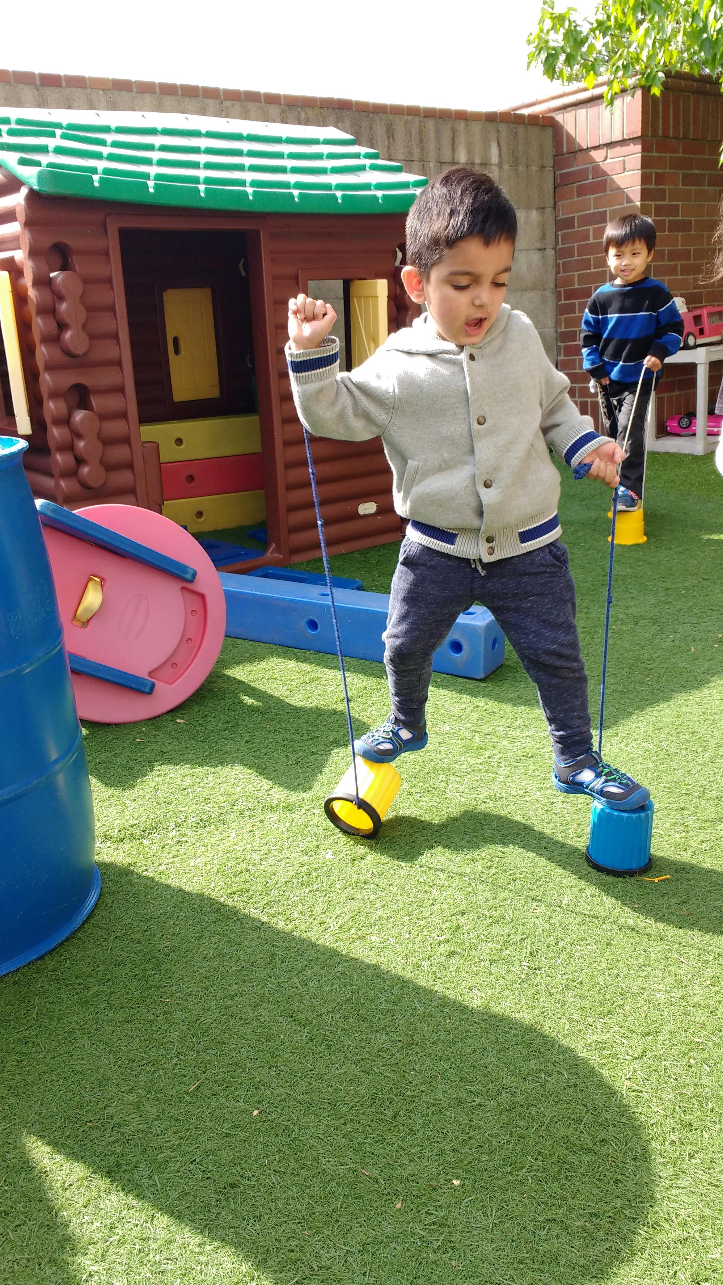 Child walking on bucket stilts on artificial grass