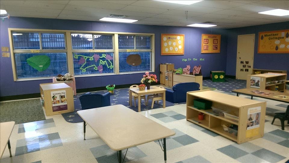 Classroom with child-sized tables and chairs, shelves, and window decorations