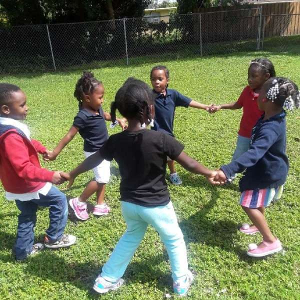 Group of children holding hands in a circle on grass
