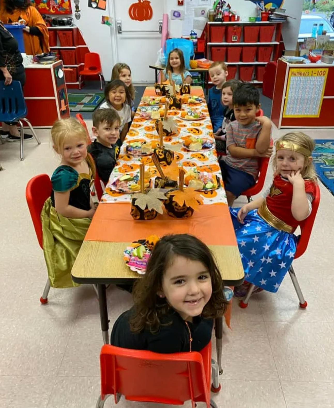 Children sitting at a long table with fall decorations in a classroom