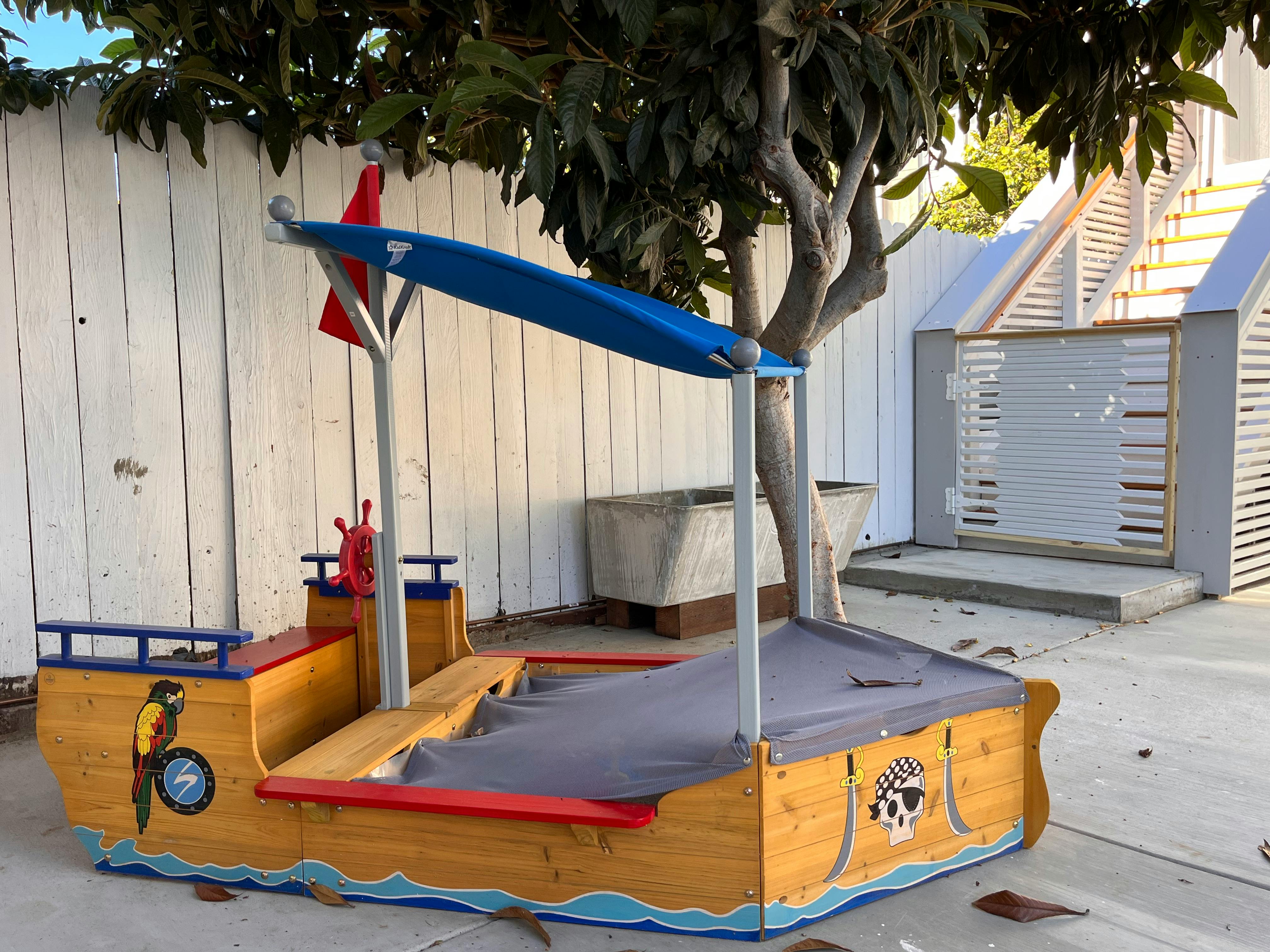 Pirate ship sandbox with a blue canopy and red flag