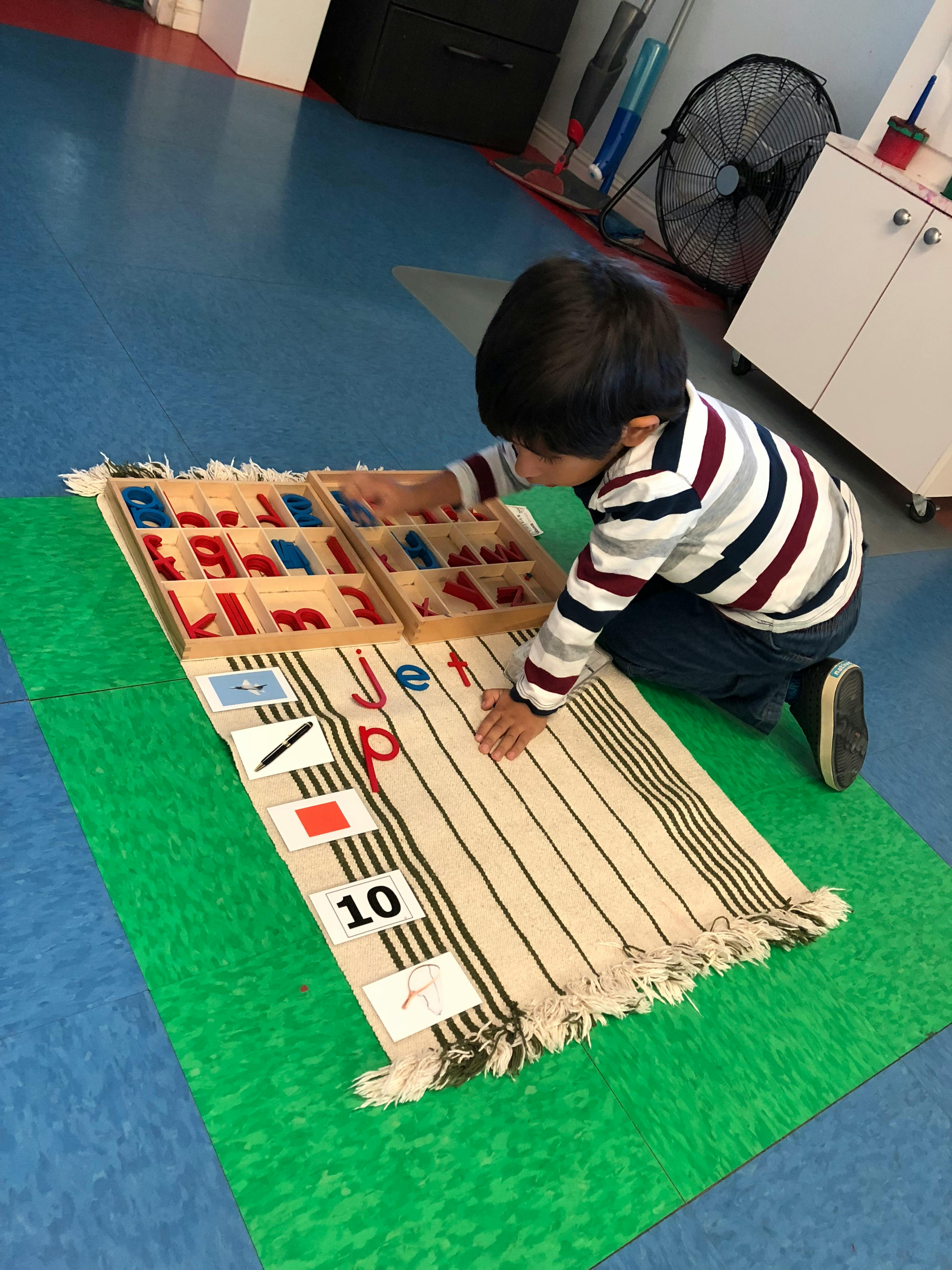 Child playing with a wooden alphabet and number set on a rug