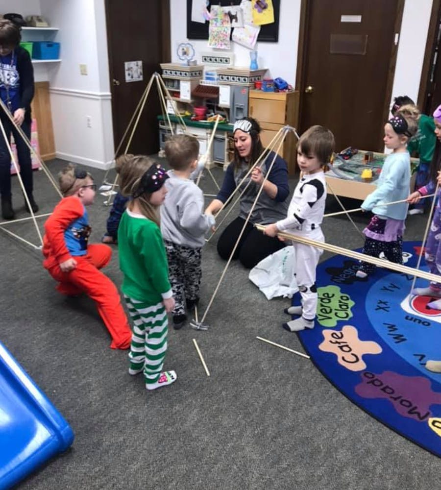 Adult and children building a structure with sticks and string