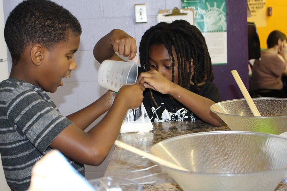 Two children pouring liquid into a bag