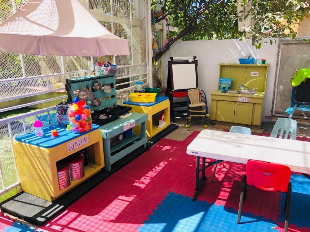 Outdoor play area with colorful toy kitchen sets and tables