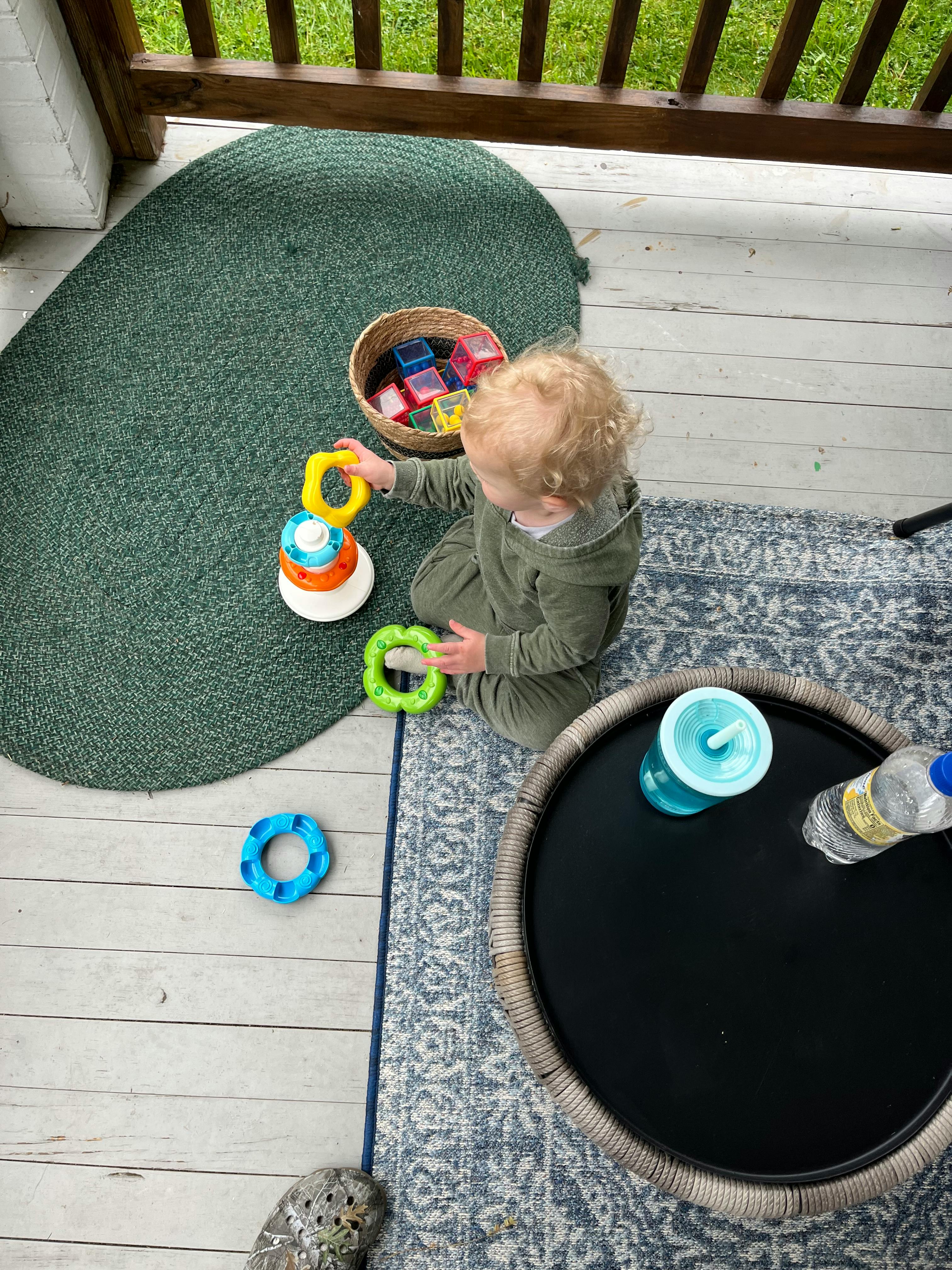 Child playing with stacking rings on a rug