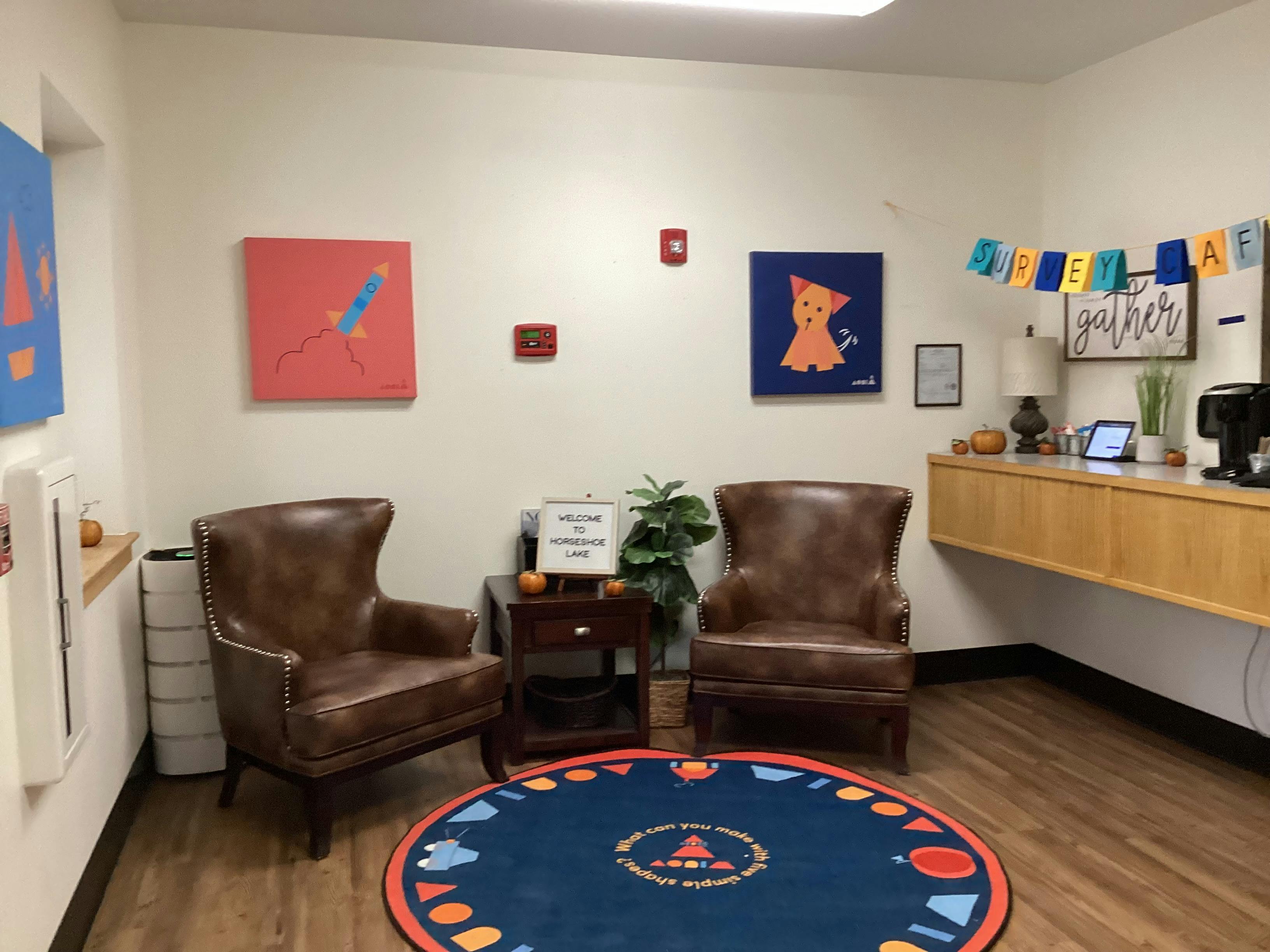 Two brown leather armchairs with a side table between them, on a circular rug