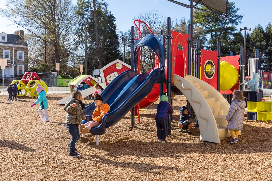 Children playing on a playground slide and climbing structure