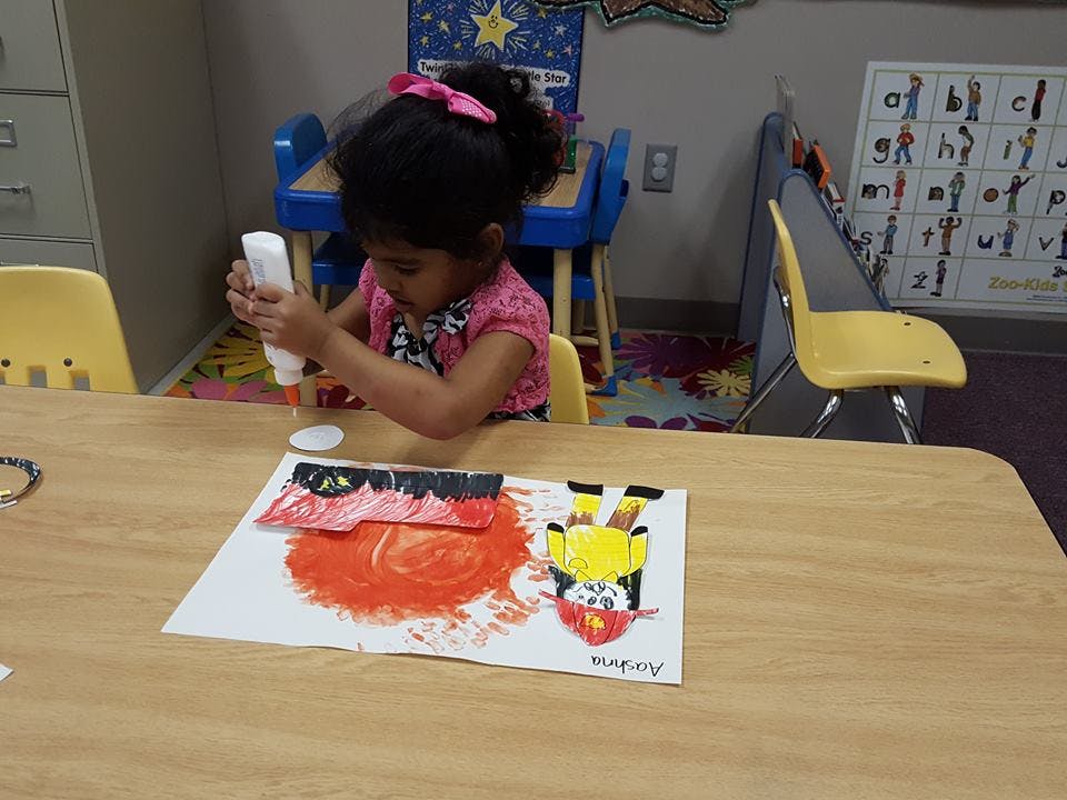 Child applying glue to paper in a classroom