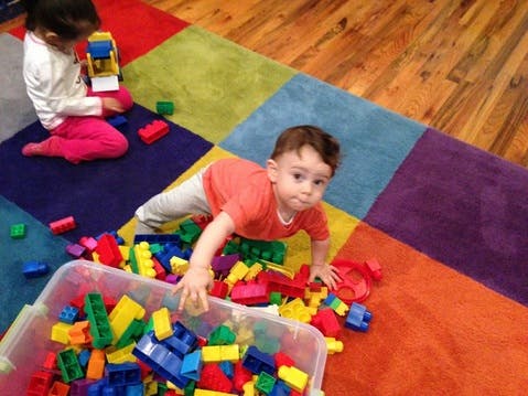 Child playing with colorful building blocks on a patterned rug