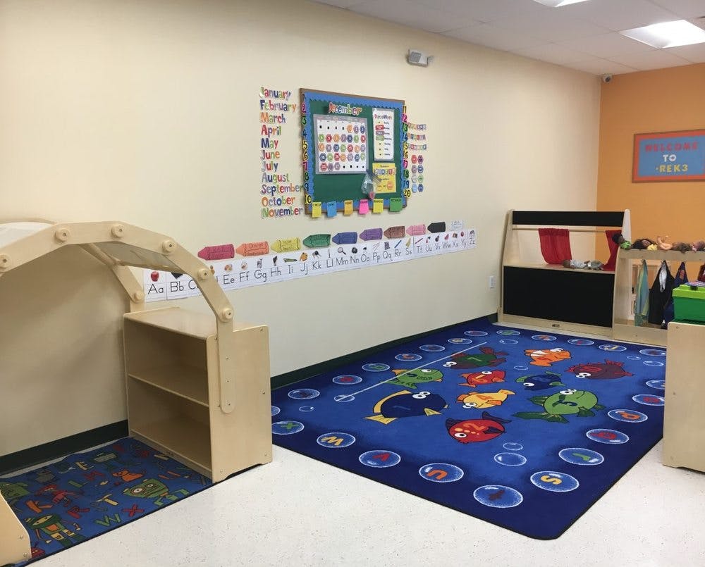 Classroom with a blue rug, calendar on the wall, and wooden shelves