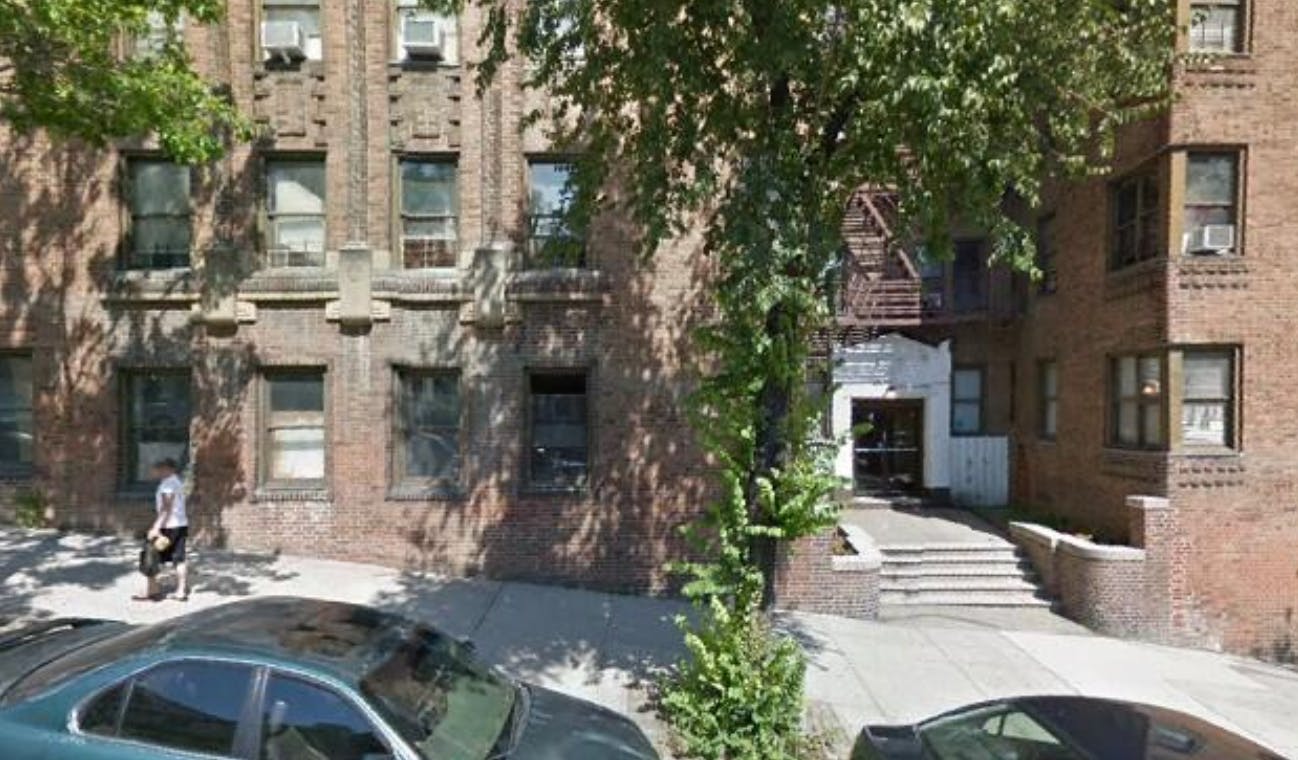 Brick building with a person walking on the sidewalk and cars parked