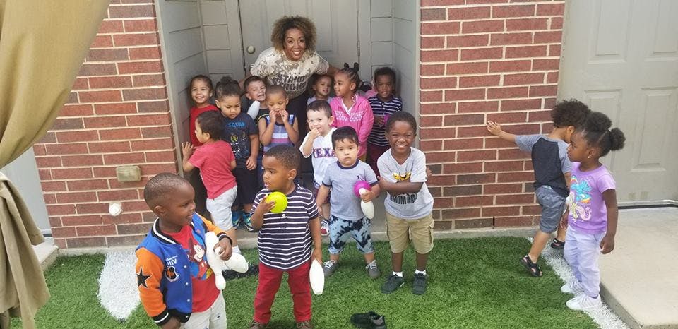 Adult and group of children standing outside a brick building