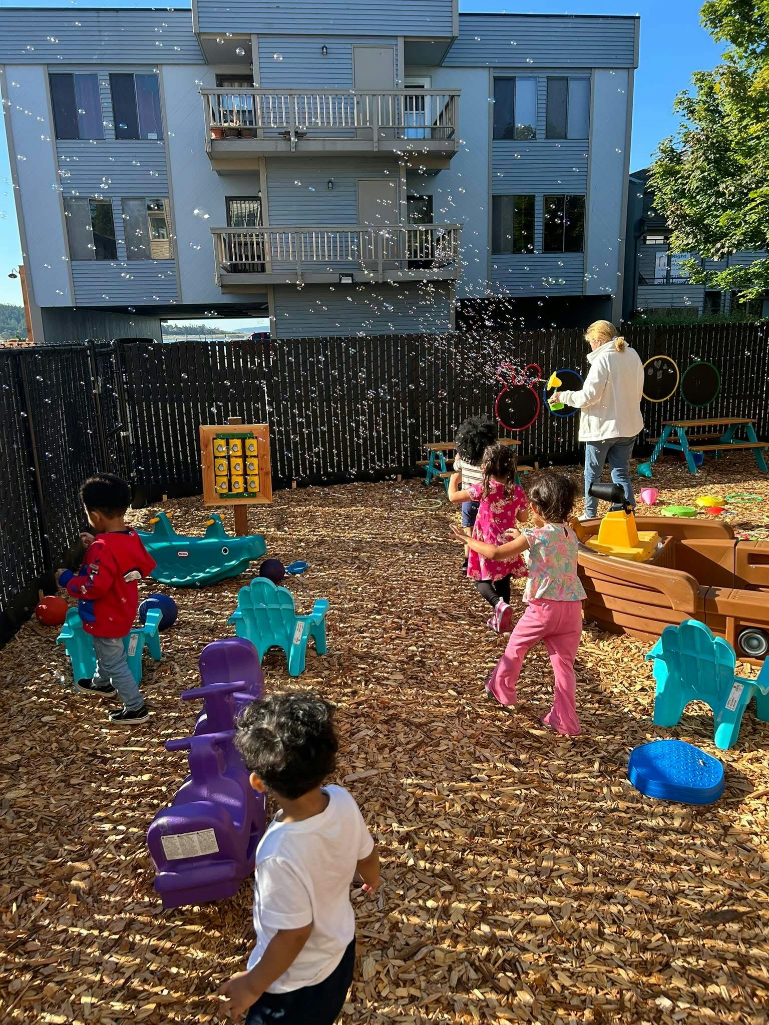 Adult and children playing with bubbles in an outdoor play area