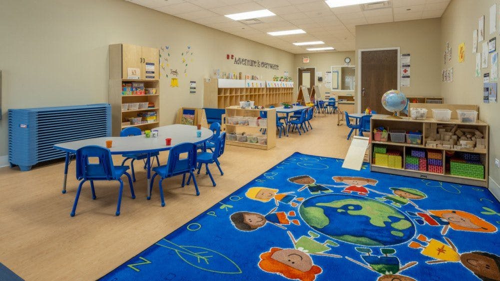 Classroom with tables, chairs, and a blue rug with a world map design
