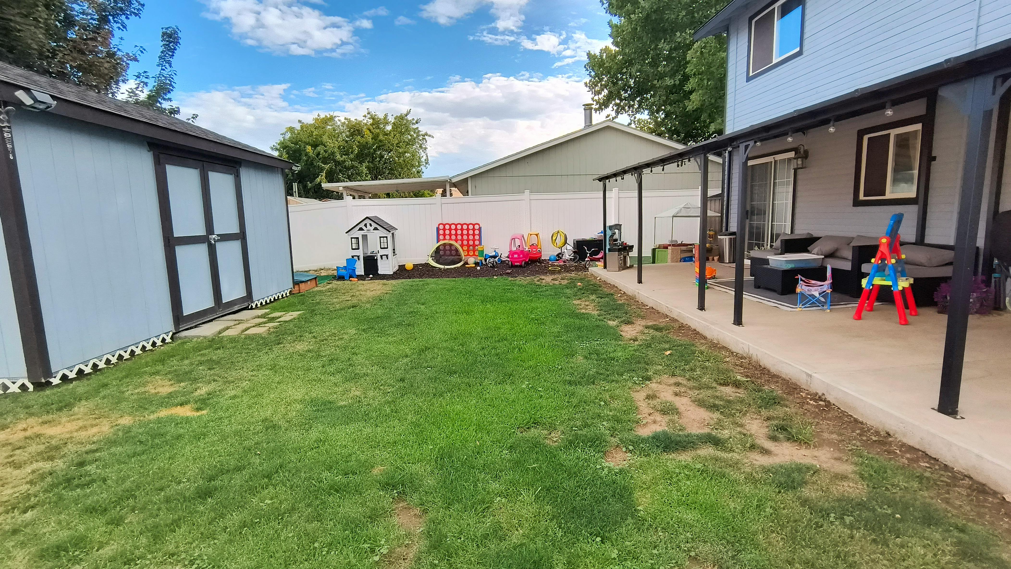 Backyard with grass lawn, outdoor furniture, and child toys
