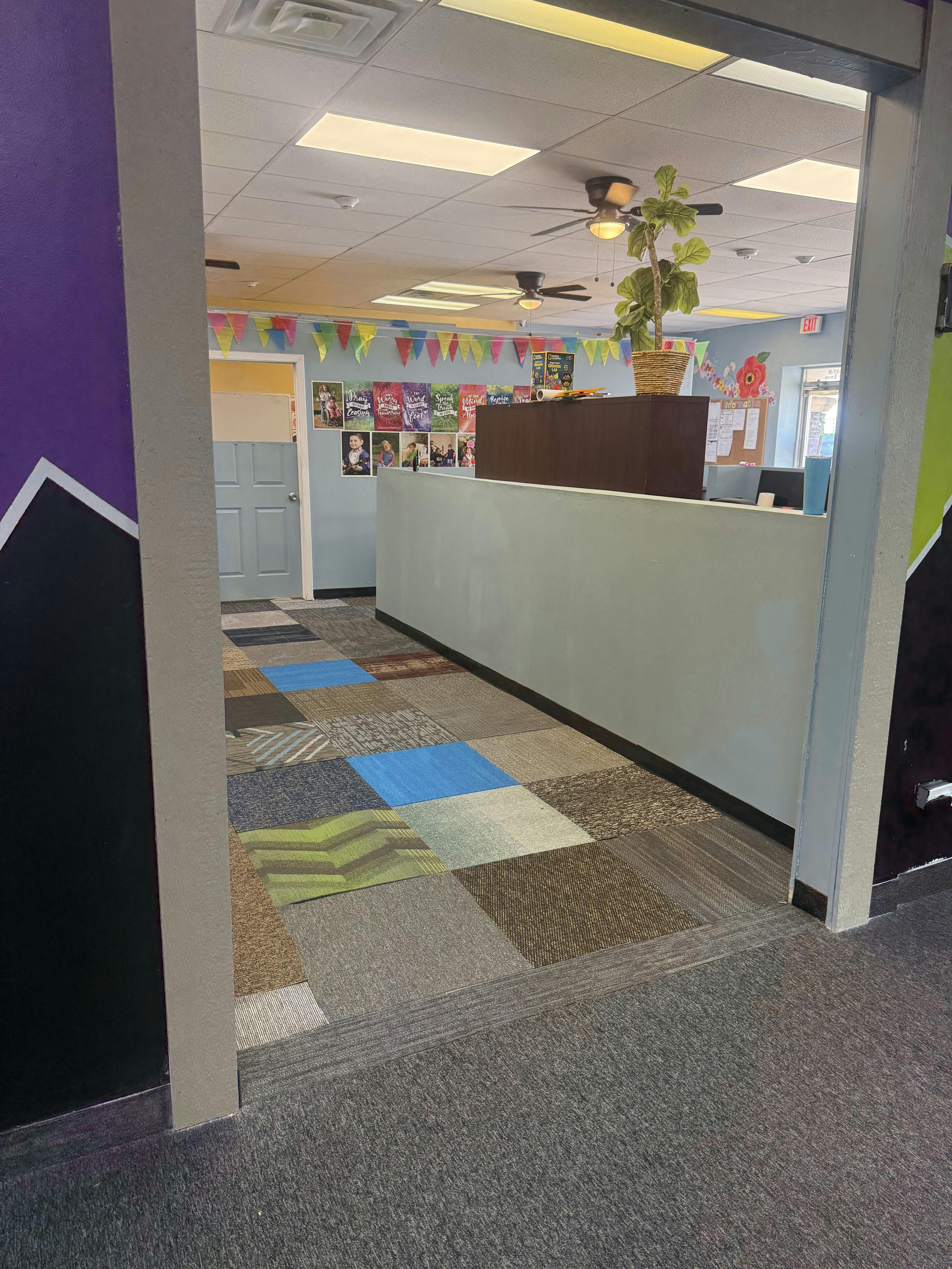 Interior view of a room with colorful carpet tiles and a reception desk