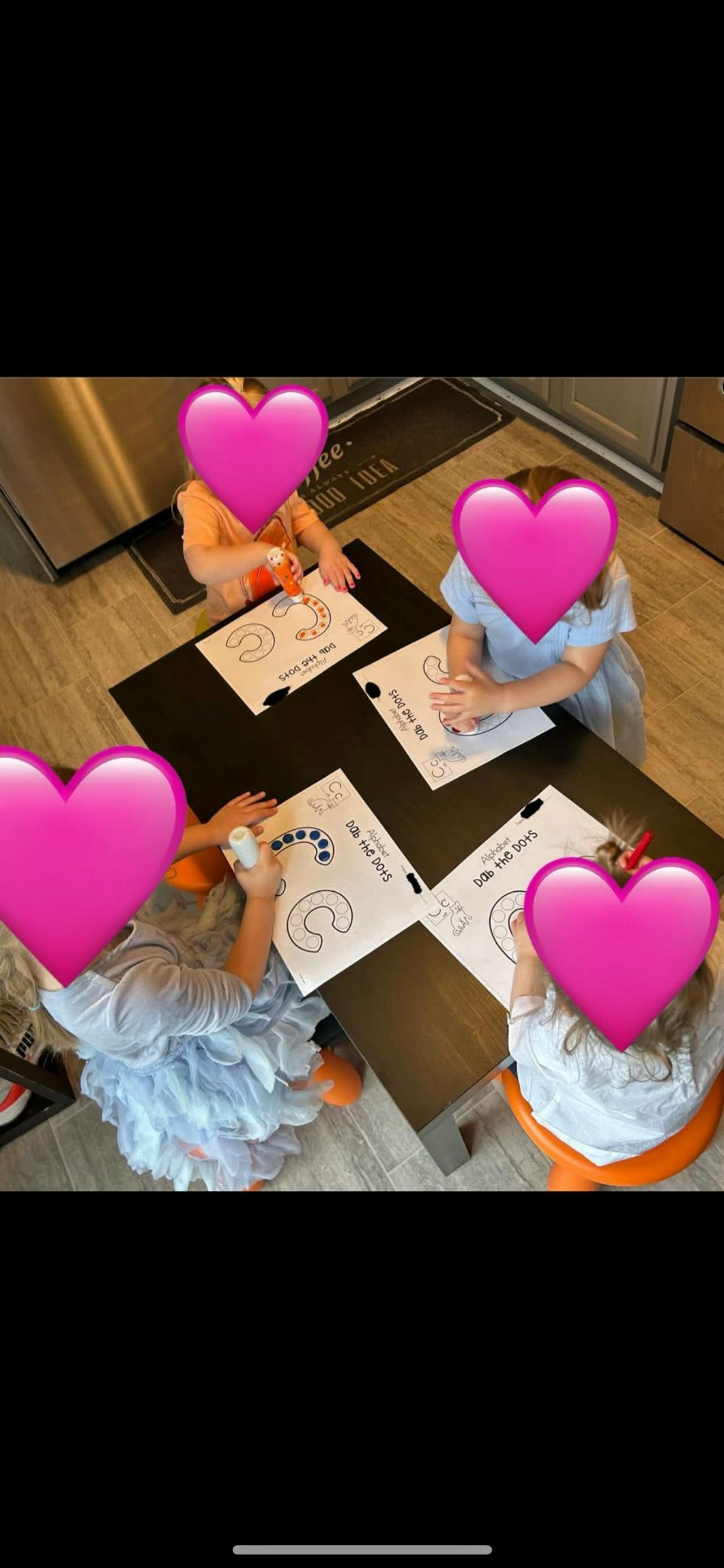 Four children sitting at a table doing an activity with paper