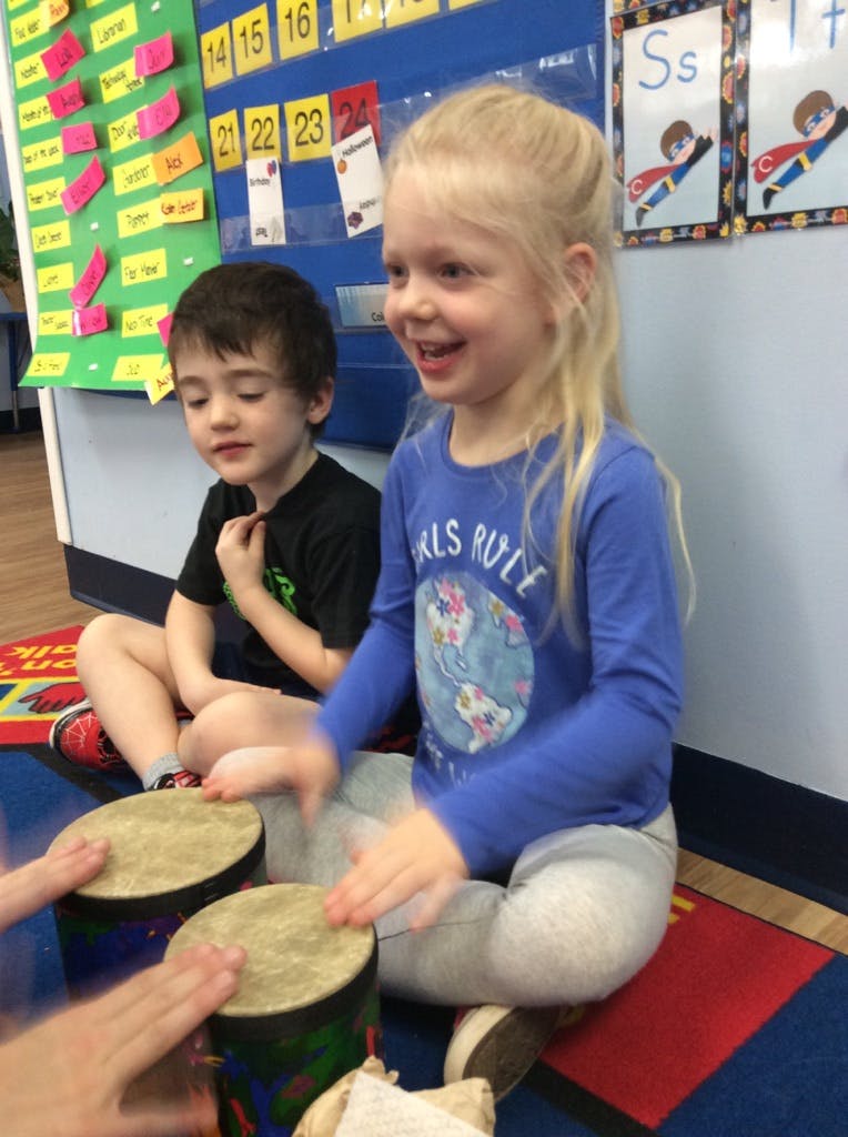 Two children playing drums in a classroom