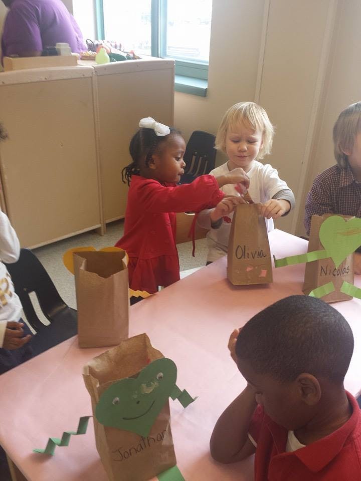 Two children at a table decorating paper bags