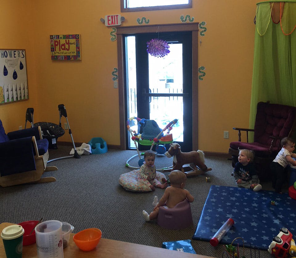 Multiple children playing on the floor in a room with toys